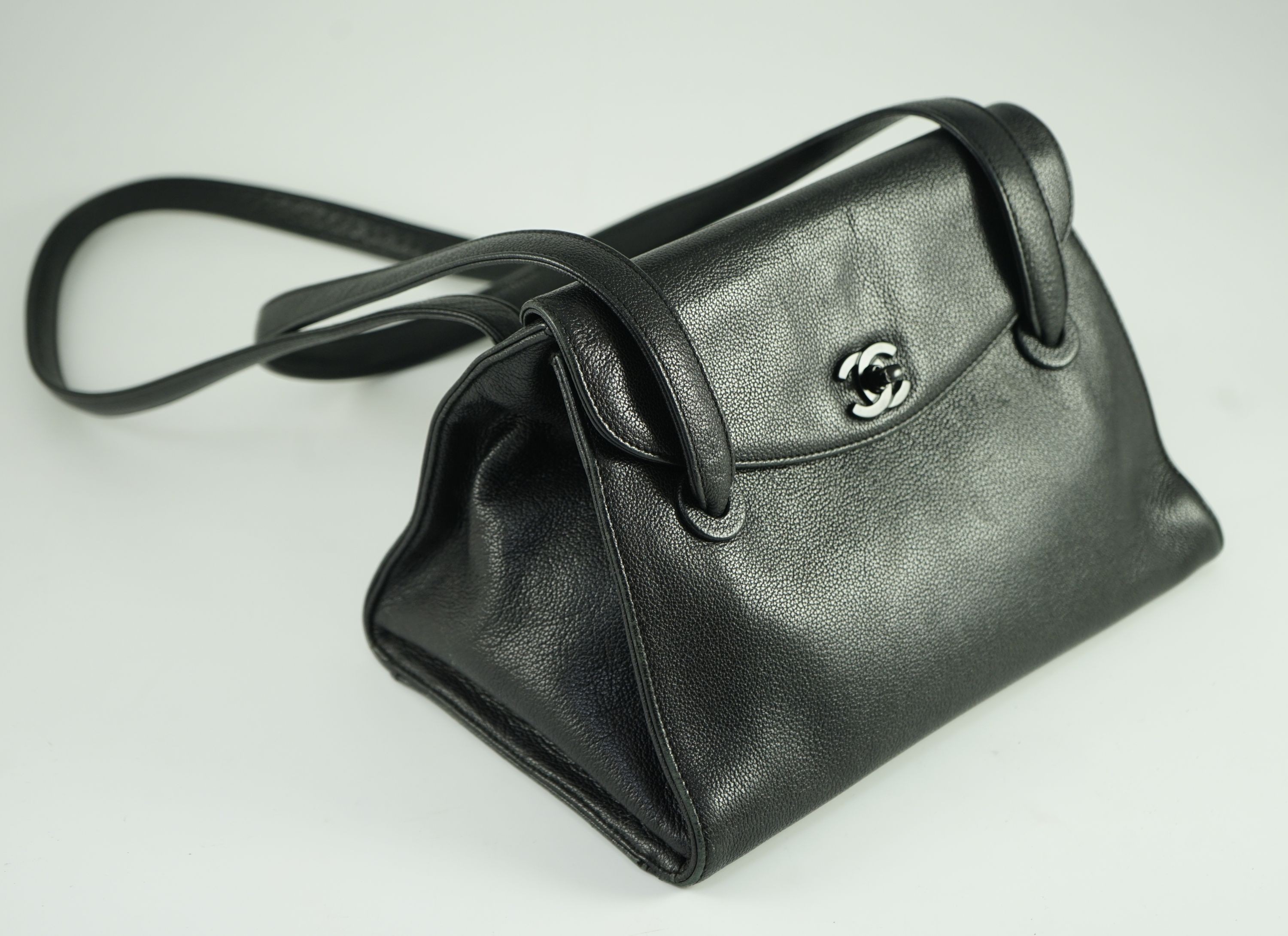 A black Chanel shoulder bag with two straps and Chanel logo lock